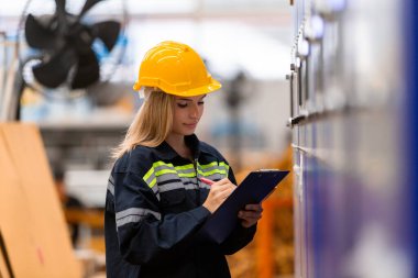 Kadın kağıt deposu çalışanı CNC otomasyonunda bilgisayar sistemli depolama ürünlerinin depolandığı depo ürünlerinde pano kontrol kalitesi ve karton miktarına not alıyor. Kağıt üretim hattındaki büyük endüstri.