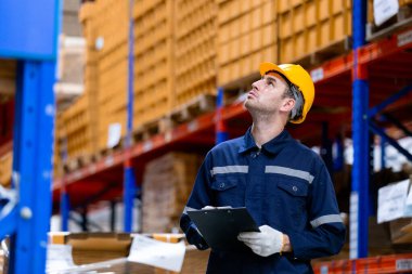 Adam kağıt deposu işçisi elinde tablet tutuyor. Kaliteyi kontrol ediyor. Depodaki stokları sayıyor. Kağıt üretiminde büyük endüstri.