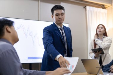 Çağdaş ofis ortamında mali raporları ve çizelgeleri tartışan bir grup profesyonel iş toplantısına katıldı. İstatistik ve şirket büyüme grafiklerinin beyin fırtınası ve analizi