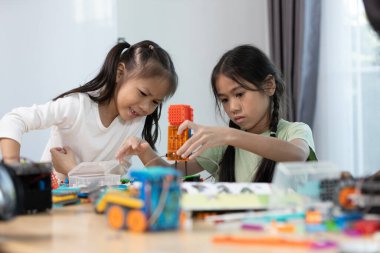 İki Asyalı kız renkli bir STEM robotik projesinde birlikte çalışarak, yaratıcılık, mühendislik becerileri ve problem çözme becerilerini geliştirmek için parçaları birleştirmeye odaklanıyorlar..