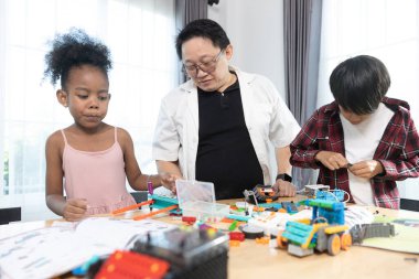 Öğretmen çeşitli öğrencilere renkli STEM robotik projeleri inşa etmede, yaratıcılığı, mühendislik becerilerini ve takım çalışmasını aktif öğrenme faaliyetleriyle teşvik etmede rehberlik ediyor.