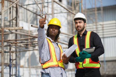 İki inşaat mühendisi açık hava planlarını tartışıyor. Bir puan ilerideyken diğeri gerçek şantiyede takım çalışması, planlama ve denetimi ön plana çıkarıyor..