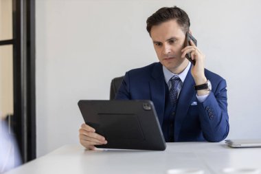 Resmi takım elbiseli kendine güvenen işadamı dijital tablet hakkındaki bilgileri kontrol ederken, modern iletişimi ve kurumsal bir ortamda birden fazla görevi temsil ediyor..