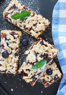 Nane şekeriyle süslenmiş siyah bir tabakta reçelli ev yapımı turta. Dikey.