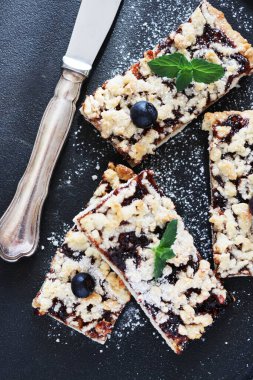 Nane şekeriyle süslenmiş siyah bir tabakta reçelli ev yapımı turta. Dikey.