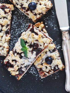 Nane şekeriyle süslenmiş siyah bir tabakta reçelli ev yapımı turta. Dikey.