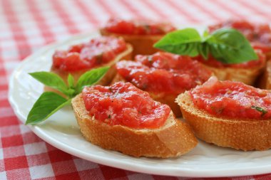 Beyaz tabakta fesleğenle süslenmiş taze domatesli