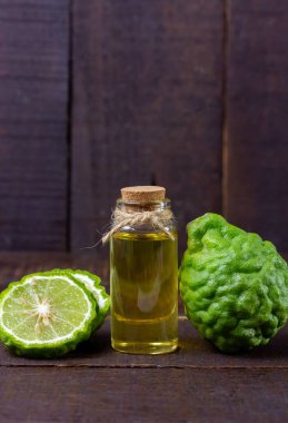 Şişede Bergamot yağı ve kırsal ahşap arka planda taze bergamot meyvesi..