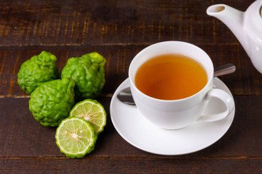 Bergamot çayı ya da seramik fincanda Earl Grey çayı ve kırsal ahşap masada dilimlenmiş taze bergamot meyvesi..