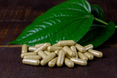 Piper sarmentosum ya da kırsal ahşap arka planda yeşil yapraklı yaban yaprağı kapsülü.