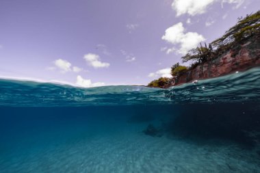 Beyaz bulutlu mavi gökyüzünün arka planında deniz dalgaları