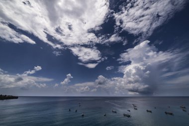 Curacao ve Karayipler 'in etrafındaki turkuaz denizin üzerinde uçan bulutlarla dolu sağanak manzarası.