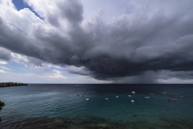 Curacao ve Karayipler 'in etrafındaki turkuaz denizin üzerinde uçan bulutlarla dolu sağanak manzarası.