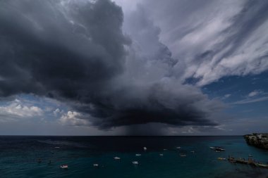 Curacao ve Karayipler 'in etrafındaki turkuaz denizin üzerinde uçan bulutlarla dolu sağanak manzarası.