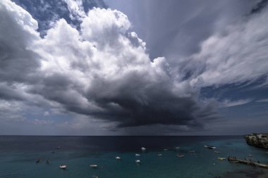Curacao ve Karayipler 'in etrafındaki turkuaz denizin üzerinde uçan bulutlarla dolu sağanak manzarası.