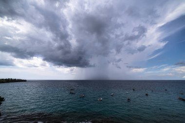 Curacao ve Karayipler 'in etrafındaki turkuaz denizin üzerinde uçan bulutlarla dolu sağanak manzarası.