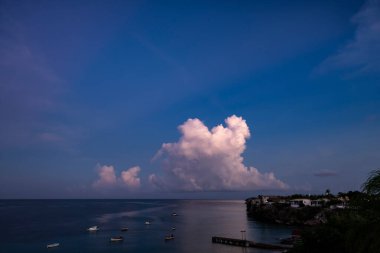 Curacao ve Karayipler 'in etrafındaki turkuaz denizin üzerinde uçan bulutlarla dolu sağanak manzarası.