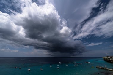 Curacao ve Karayipler 'in etrafındaki turkuaz denizin üzerinde uçan bulutlarla dolu sağanak manzarası.