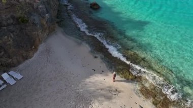 Karayipler 'deki tropikal bir adada beyaz plajda yürüyen bir kadın.