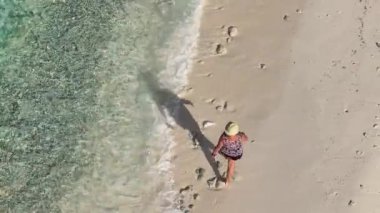 Karayipler 'deki tropikal bir adada beyaz plajda yürüyen bir kadın.