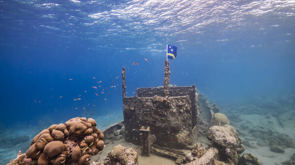 Ship wreck "Tugboat" in shallow water of coral reef in Caribbean sea with Curacao Flag, view to surface and sunbeams