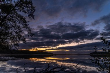 Ağaçlarla çevrili güzel bir günbatımı görüntüsü.