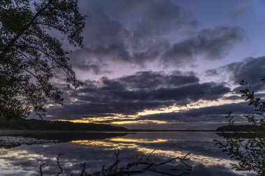 Ağaçlarla çevrili güzel bir günbatımı görüntüsü.