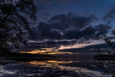 Ağaçlarla çevrili güzel bir günbatımı görüntüsü.