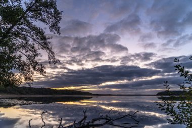 Ağaçlarla çevrili güzel bir günbatımı görüntüsü.