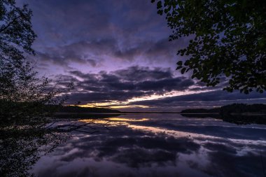 Ağaçlarla çevrili güzel bir günbatımı görüntüsü.