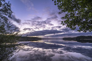 Ağaçlarla çevrili güzel bir günbatımı görüntüsü.