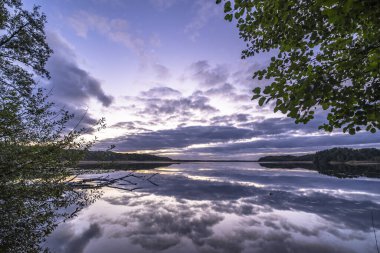Ağaçlarla çevrili güzel bir günbatımı görüntüsü.
