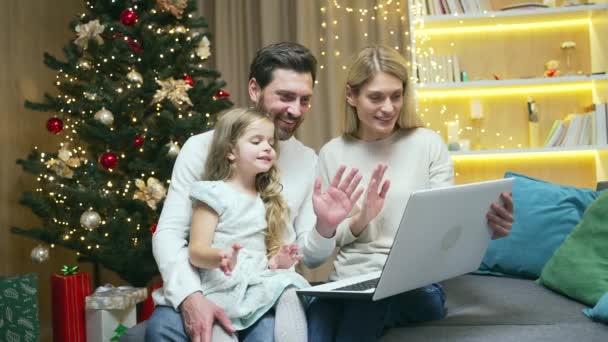 家族の親と女の子の子供はビデオ会議チャットを介してリモートでお祝いを通信オンライントークメリークリスマス家庭でラップトップコンピュータを使用して新年の冬の休日 — ストック動画