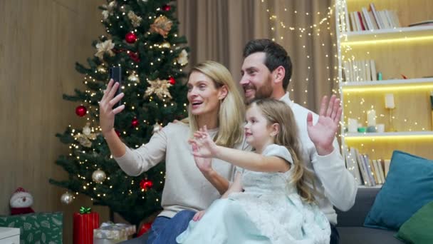 幸せな家族男性女性と女の子子供はビデオ会議チャットを介してリモートでお祝いを通信オンライントークメリークリスマスとハッピー新年自宅でスマートフォンを使用して — ストック動画