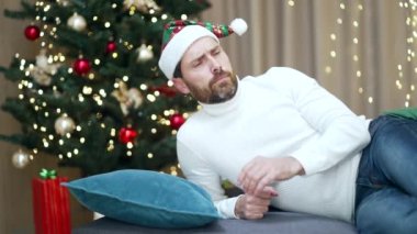 Yılbaşı partisini akşamdan kalma bir şekilde kutladıktan sonra başı ağrıyan bir adamın portresi. Mide bulantısı olan ve Noel ağacının arka planında evde sağlık sorunu olan bir erkek.