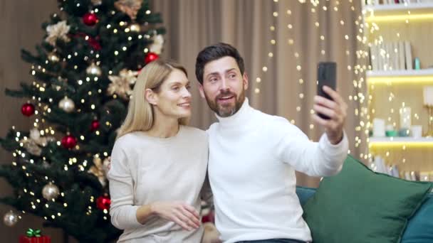 Cheerful Caucasian Couple Sitting Couch Christmas Tree Looking Smartphone Mobile — Stock Video