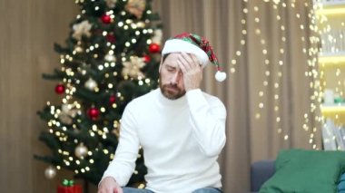 Yılbaşı partisini akşamdan kalma bir şekilde kutladıktan sonra başı ağrıyan bir adamın portresi. Mide bulantısı olan ve Noel ağacının arka planında evde sağlık sorunu olan bir erkek.