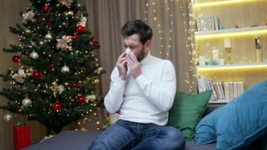 Yeni yıl arifesinde grip olmuş hasta bir adam evde tek başına oturur, hapşırır, öksürür burnu akan hasta sakallı erkek için üzgün noel günleri.