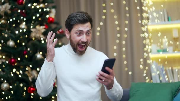 Νεαρός Ενθουσιασμένος Άνθρωπος Ευτυχής Θετικό Χαμόγελο Γιορτάσουν Νίκη Smartphone Χριστούγεννα — Αρχείο Βίντεο