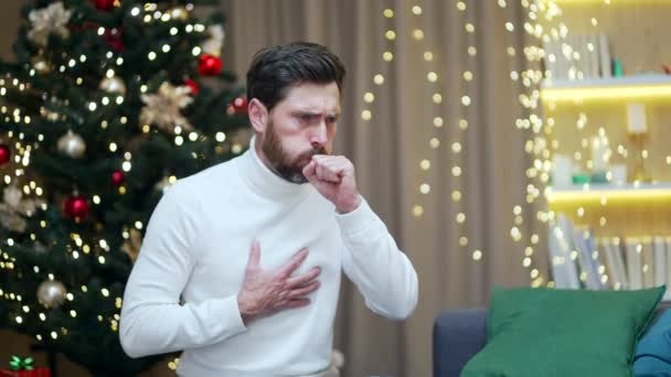 在新年假期里 男人一个人坐在沙发上 在客厅里病倒了 病性男性在冬季肺部发炎时得了感冒 — 图库视频影像