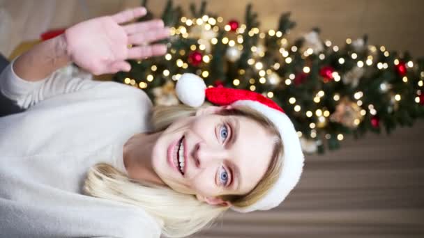 头戴圣诞礼帽的Pov女性通过视频呼叫智能手机摄像头 祝大家新年快乐 在圣诞树的背景下 用手机进行远程祝贺 — 图库视频影像