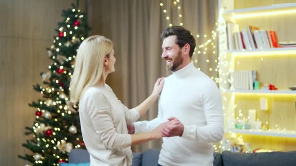 クリスマスの前夜に夫婦で一緒に踊るロマンチックなカップル一緒に過ごす新年の時間を祝う 配偶者の男と女は休日のリビングルームで家に抱擁 — ストック動画