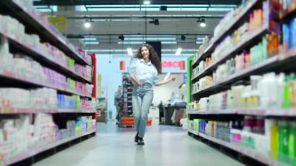 商店里快乐的年轻女性顾客在超市里走来走去 一边跳舞 一边跳着时髦的疯婆子舞 玩得很开心 — 图库视频影像