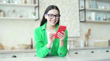 Evdeki akıllı telefondan harika haberler alırken aşırı mutlu kadın gözlerine inanamıyor. Şaşırmış şanslı kız cep telefonundan gelen mesajı okuduktan sonra çok mutlu oldu.