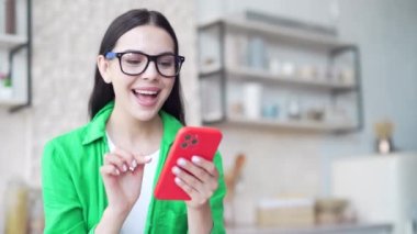 Çok mutlu bir kadın evdeki akıllı telefondan harika haberler alırken gözlerine inanamıyor. Mutfaktaki cep telefonundaki mesajı okuduktan sonra çok mutlu olan şanslı kız kapalı alanda seviniyor.