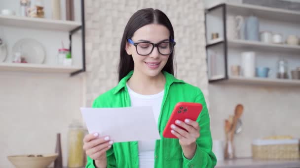 Lächelnde Junge Frau Mit Brille Die Stromrechnungen Bezahlt Und Hellen — Stockvideo