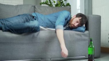 Sarhoş sakallı bir adamın portresi. Yanında bir şişeyle kanepede uyuyor. Alkolizm bağımlılığı ve kötü alışkanlıklar yüzünden akşamdan kalma.