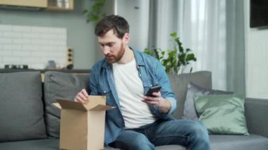 Mutlu müşteri paket karton kutudan sipariş aldı ve oturma odasındaki koltukta oturan akıllı telefonu kullanarak çevrimiçi dükkan için yorumlar bıraktı. Mükemmel servis ve teslimat konsepti. 
