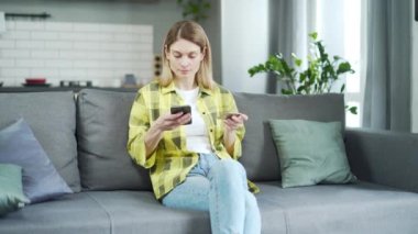 Genç ve çekici bir kadın kredi kartıyla ödemeyi evde tek başına yapıyor. Mutlu müşteri internet alışverişi yapıyor ve kolay ödeme konsepti alıyor.