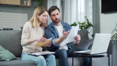 Meşgul aile oturma odasında oturuyor ve ev ekonomilerini birlikte yönetiyor. Evraklarla ilgili sorunları olan endişeli çift, mali yönetim kavramını araştırıyor.